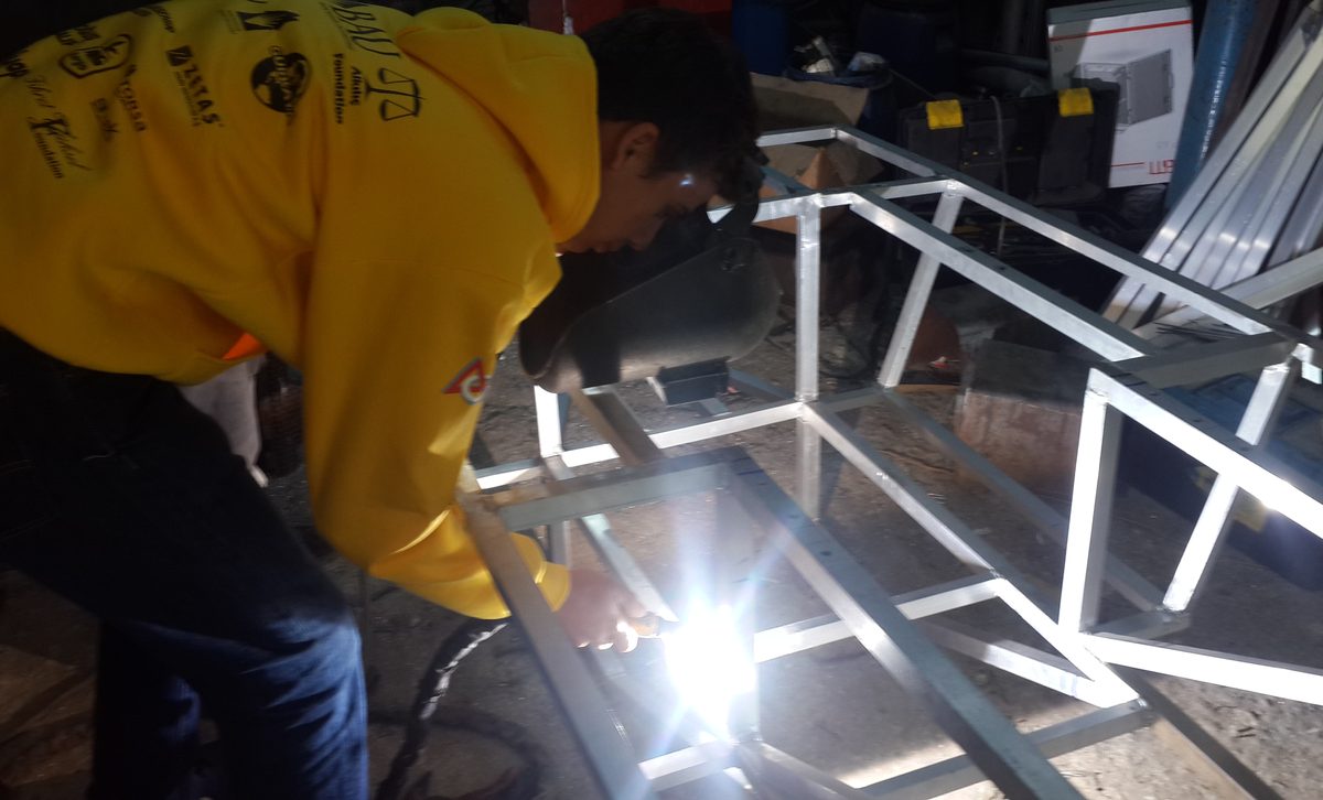 Onat Cakici welding the aluminum space-frame chassis of a full-size solar car during high school